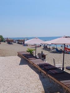 een strand met tafels, stoelen en parasols bij Kiki's Village House in Néa Karváli