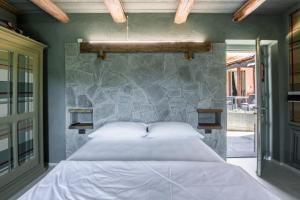 a bedroom with a large bed and a stone wall at Segnavento -Rooms and Suites B&B a Manta vicino Saluzzo in Manta