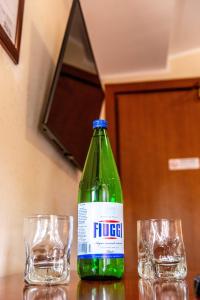 eine grüne Flasche neben zwei Gläsern auf dem Tisch in der Unterkunft Hotel Dei Pini in Fiuggi