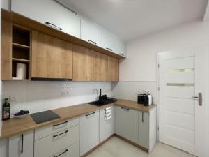 a kitchen with white cabinets and a wooden counter top at URBAN APARTMENTS PREMIUM, Opolska 10 No 77B, Free Garage, Self Check-in in Katowice