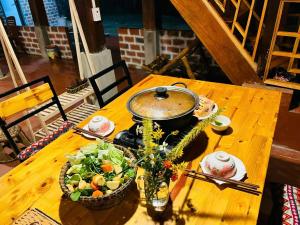 a wooden table with a bowl of salad and a pot at Retreat Home Bản Dọi Mộc Châu in Mộc Châu
