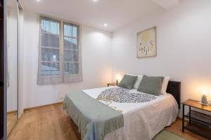 ein weißes Schlafzimmer mit einem Bett und einem Fenster in der Unterkunft Coeur de Provence - Appt climatisé in Draguignan
