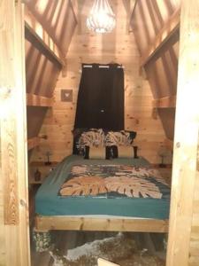 um quarto com uma cama num chalé de madeira em Gîte et Chambres d'hôtes du Domaine du Val Bruant em Arc-en-Barrois