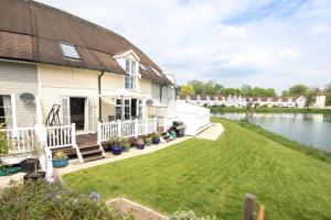 a house with a large yard and a lake at Isis Lakes 07, Carpe Diem in South Cerney
