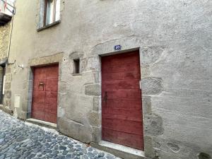 zwei rote Türen an der Seite eines Gebäudes in der Unterkunft Perle de lune in Billom