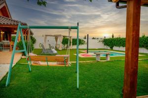 a swing in a yard with a pool at Madera y Miel Casa Rural con niños en Puy du Fou in Guadamur