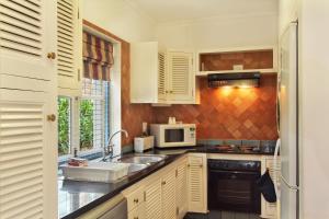 cocina con armarios blancos, fregadero y microondas en Caribbean Estates Holiday Resort, en Port Edward