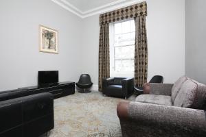 a living room with a couch and a tv and a window at Cairn Hotel & Apartments in Edinburgh