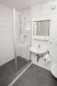 a white bathroom with a shower and a sink at Appartis - Boardinghouse am Klostersee in Sindelfingen