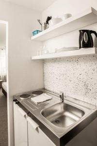 a kitchen with a stainless steel sink and shelves at Appartis - Boardinghouse am Klostersee in Sindelfingen