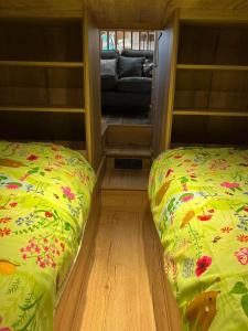 Llansantffraid-ym-MechainにあるHoneybee Homeのソファ付きの小さな部屋のベッド2台