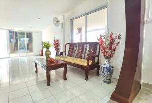 a living room with a bench and a vase with flowers at Love In Kan in Wang Khanai