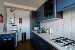 - une cuisine avec des placards bleus, un évier et une cuisinière dans l'établissement Appartement Majelle, à Egmond aan Zee