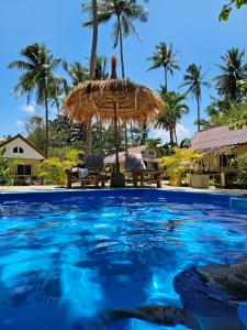 a swimming pool with an umbrella and palm trees at The Mellow Mango in Ko Lanta