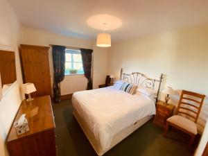 a bedroom with a bed and a chair and a window at Forge Cottage in Rothbury