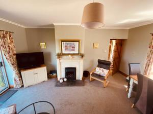 a living room with a fireplace and a flat screen tv at Forge Cottage in Rothbury