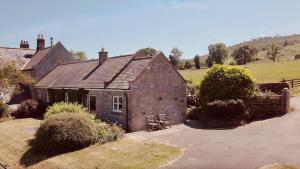 ein altes Backsteinhaus mit einem Feld im Hintergrund in der Unterkunft Forge Cottage in Rothbury