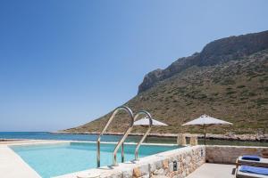 una piscina con sombrilla y montaña en Villa Amina, en La Canea