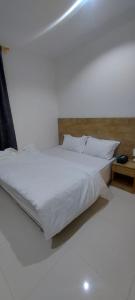 a bed with white sheets and pillows in a room at سما رفحاء للشقق المخدومة in Rafha