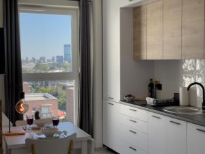 una cucina con tavolo e una grande finestra di URBAN APARTMENTS PREMIUM Baildona 18B with GARAGE a Katowice
