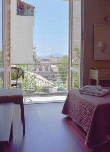 een slaapkamer met een bed en een groot raam bij City Center Hotel in Kalamata