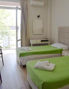 um quarto com duas camas com lençóis verdes e uma janela em City Center Hotel em Kalamata