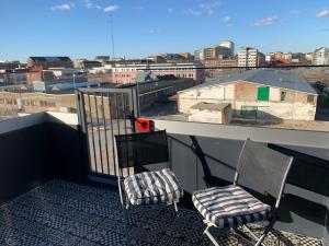 two chairs on a balcony with a view of a city at Lottas Beautiful Penthouse Apartment in Malmö