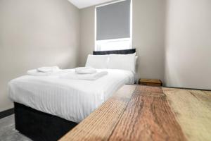 1 dormitorio con cama con sábanas blancas y mesa de madera en Sleek and Stylish Converted 1Bed in Old Boiler Factory - Flat 4 en Nottingham