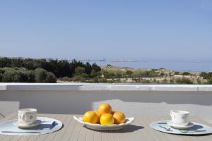 eine Schale Obst auf einem Tisch mit zwei Tassen in der Unterkunft Costa Azzurra Gallipoli in Gallipoli + 4 Fotos
