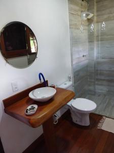 a bathroom with a sink and a toilet and a mirror at Pousada Refúgio Eça-Porã in Serra Grande
