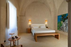 um quarto com uma cama branca e uma grande janela em Tre Bacili - L'ospitalità in Dimora em Spongano