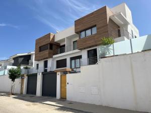 a house with a white wall and a fence at OASIS PRESTIGIO in Huétor Vega