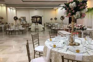 - une salle de banquet avec des tables blanches, des chaises et des fleurs dans l'établissement Howard Johnson by Wyndham Barranquilla Versalles, à Barranquilla
