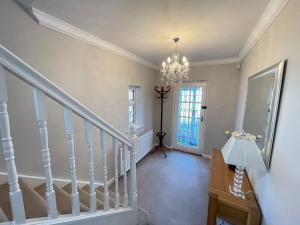 um corredor com uma escada com um lustre em Seaview House, Tynemouth - Luxury Family Holiday Home em Tynemouth