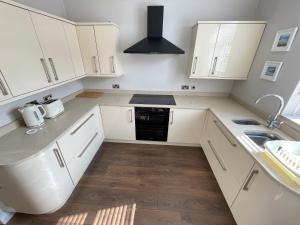 eine weiße Küche mit weißen Schränken und einem Waschbecken in der Unterkunft Seaview House, Tynemouth - Luxury Family Holiday Home in Tynemouth