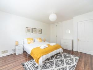 um quarto branco com uma cama grande e um cobertor amarelo em Pass the Keys Stylish Apt in quiet cul de sac em Surbiton