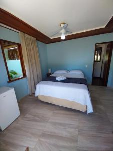 een slaapkamer met een bed en een plafondventilator bij Pousada Refúgio Eça-Porã in Serra Grande