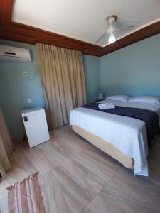 a bedroom with a large bed and a night stand at Pousada Refúgio Eça-Porã in Serra Grande