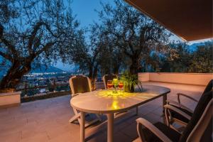una mesa en un patio con copas de vino en Casa tra gli Olivi en Arco