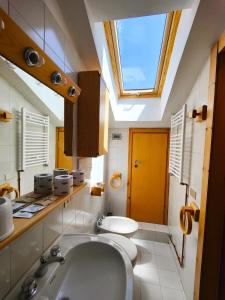 a bathroom with a sink and a toilet and a skylight at Hostdomus - Sansicario C 14 in Cesana Torinese