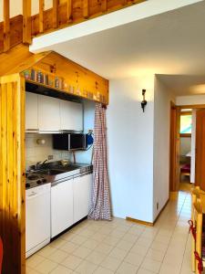 a kitchen with white cabinets and a stove top oven at Hostdomus - Sansicario C 14 in Cesana Torinese