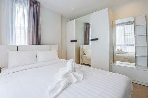 a white bedroom with a large white bed and a mirror at O2 Hotel Maesot in Mae Sot