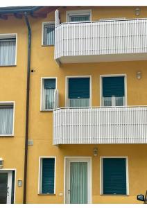 un edificio amarillo con balcones blancos en AppArt 24 city center parking and Sea en Lignano Sabbiadoro
