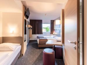 a hotel room with two beds and a desk at B&B Hotel Regensburg-City in Regensburg +23 photos