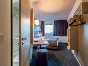 ein Hotelzimmer mit 2 Betten und einem Tisch in der Unterkunft B&B Hotel Regensburg in Regensburg