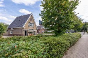 een gebouw met een boom naast een bakstenen stoep bij Bed & keuken De Vos in Delden