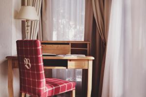 a desk with a red chair next to a window at Burg Hotel Oberlech in Lech am Arlberg