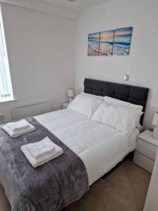 a bedroom with a large bed with two towels on it at Elegant City Centre Flat in Leeds