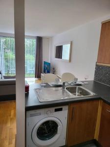 a kitchen with a sink and a washing machine at Elegant City Centre Flat in Leeds