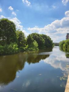 a river with trees and a bridge in the background at Elegant City Centre Flat in Leeds